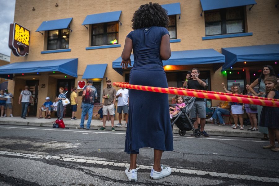 A woman watches a hula hoop performer on the street at MangoFest, Lake Worth Beach